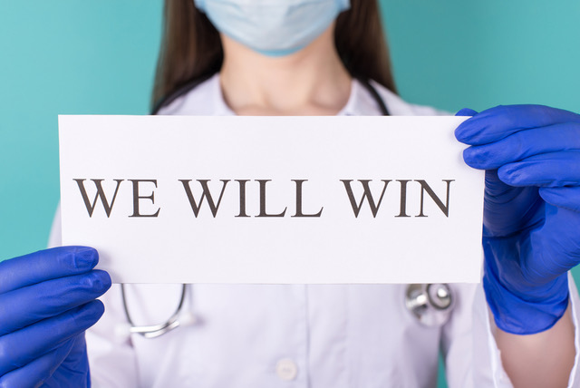 Nurse with 'We Will Win' sign